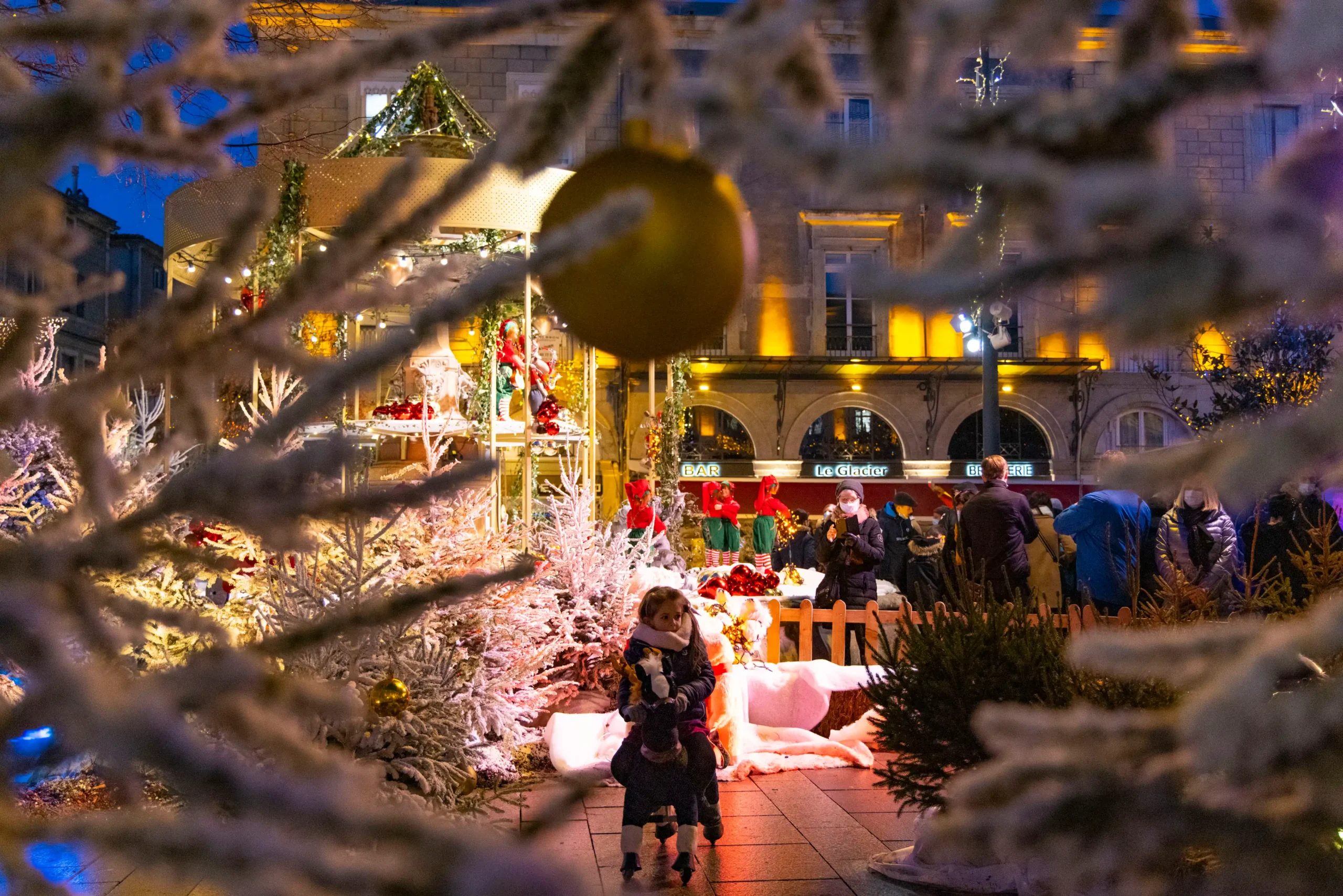 Photo montrant une petite fille sur un cheval a roulette lors du marché de noël.