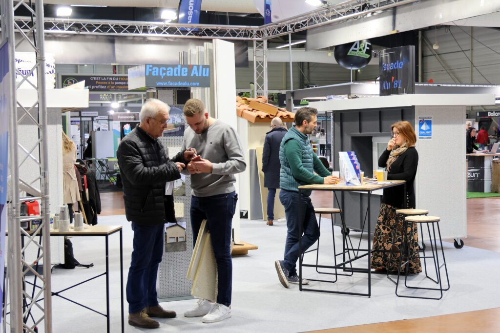 L'image montre un stand ou deux commerciaux en isolation parlent à deux clients au salon de l'habitat et des loisirs